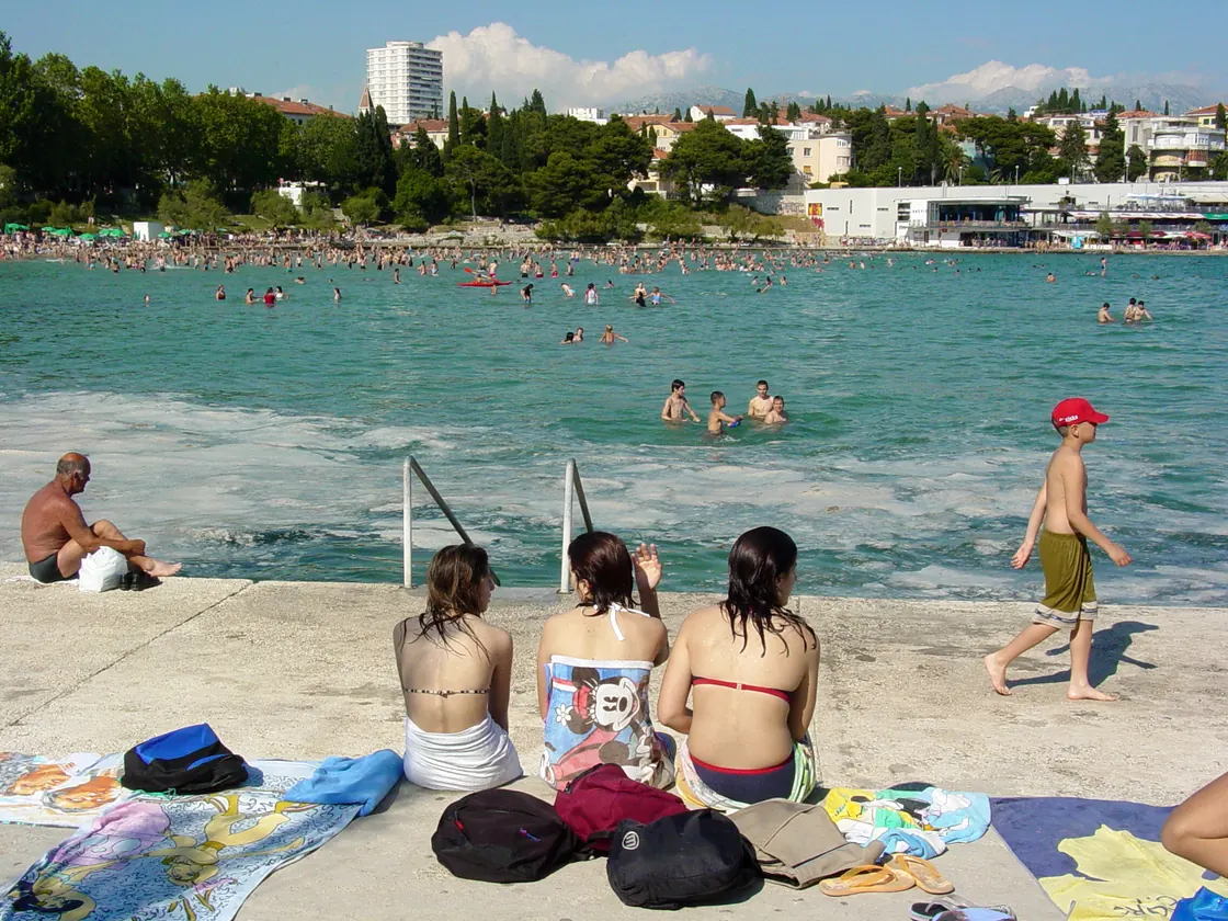 Sunbathers on the sand at Bačvice with the beachfront buildings behind