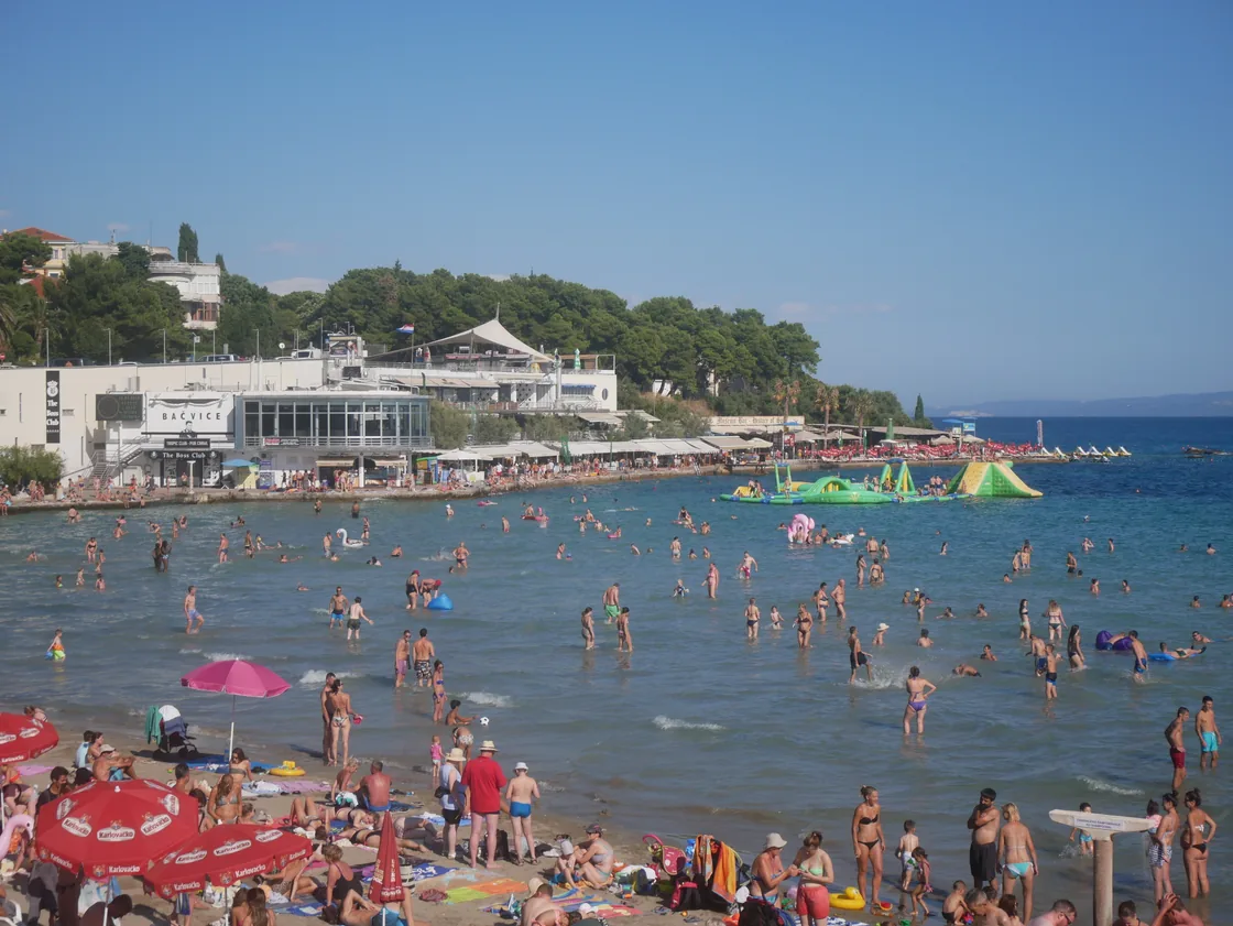 Crowds on the sand at Bačvice with the white multi-level beachfront building behind