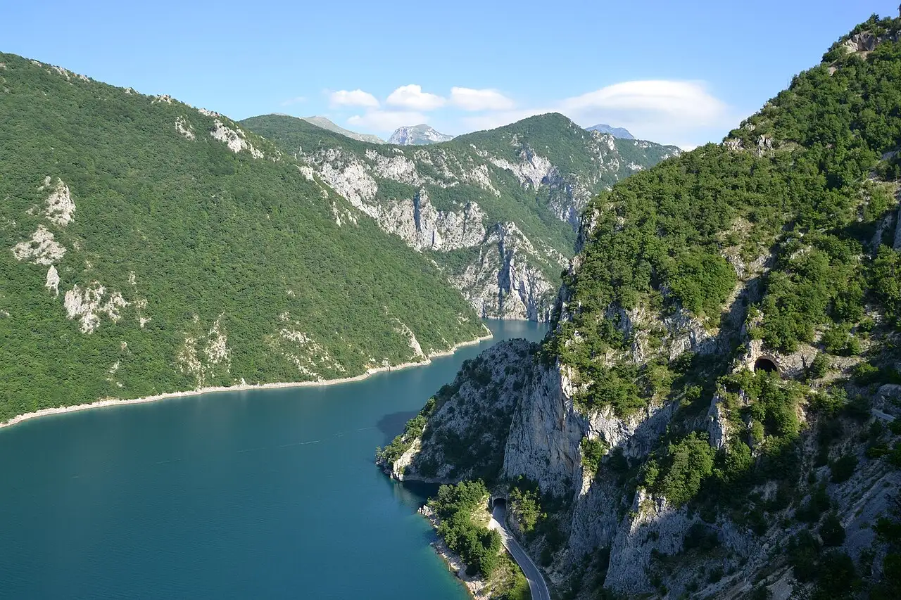 The turquoise Piva reservoir winding between steep forested mountains in Montenegro on the road from Bosnia