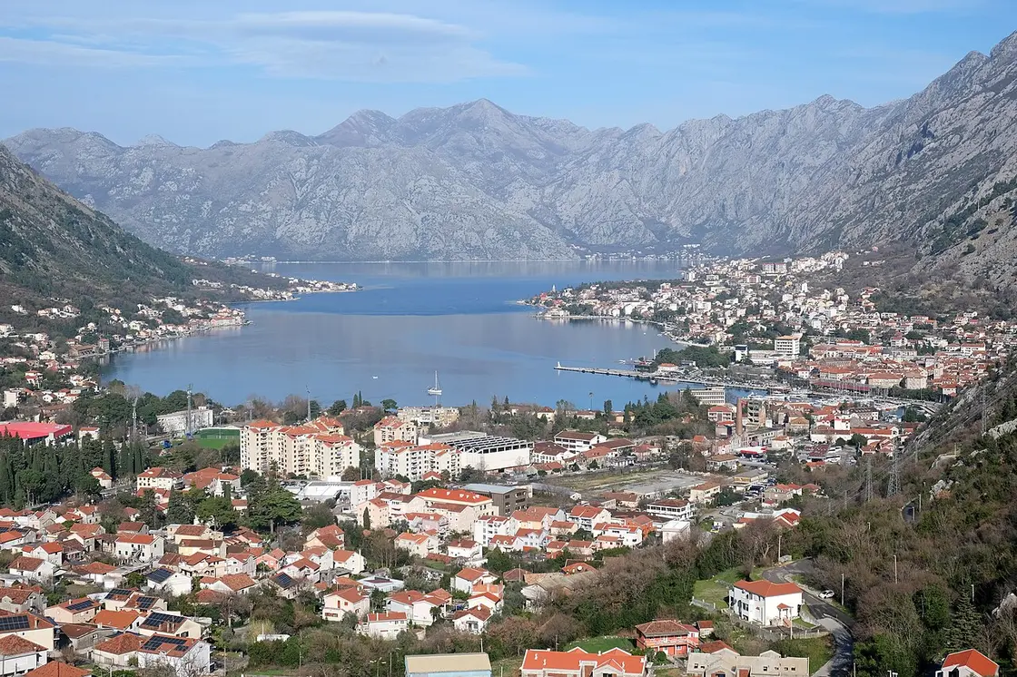 The Bay of Kotor seen from above, still water ringed by steep grey mountains