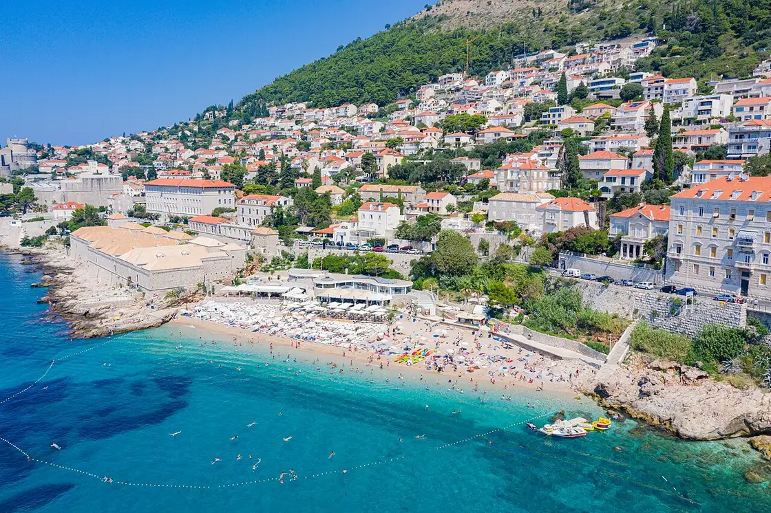 Banje pebble beach below the walls of Dubrovnik with Lokrum island offshore