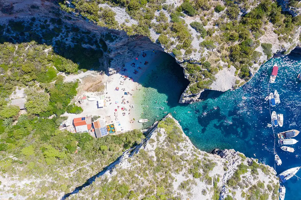 The narrow cliff gateway of Stiniva cove on Vis opening onto a pebble beach and clear water