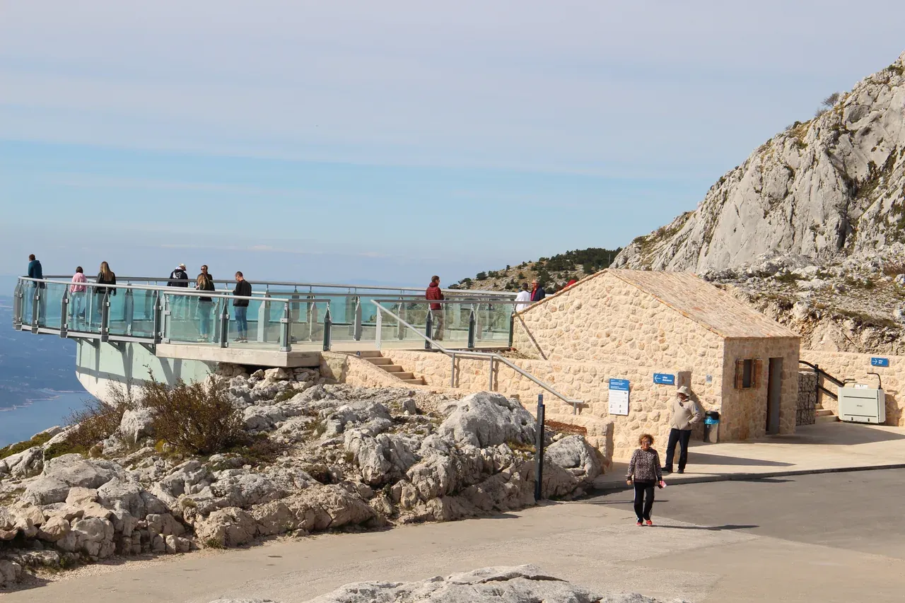 The Biokovo Skywalk platform from the side, with its stone service building and the mountain path beside it
