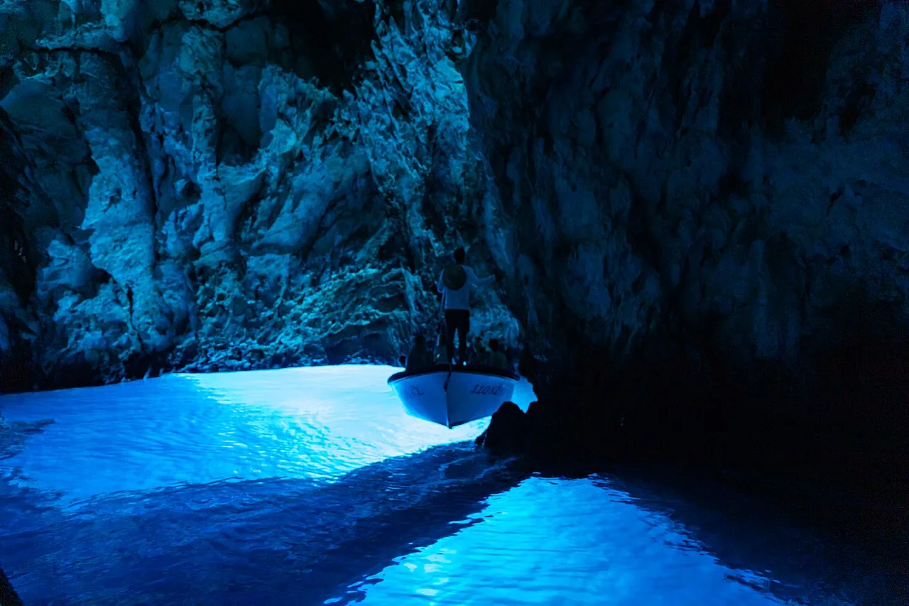 The glowing blue water inside the Blue Cave with a boat silhouetted against the bright pool of light