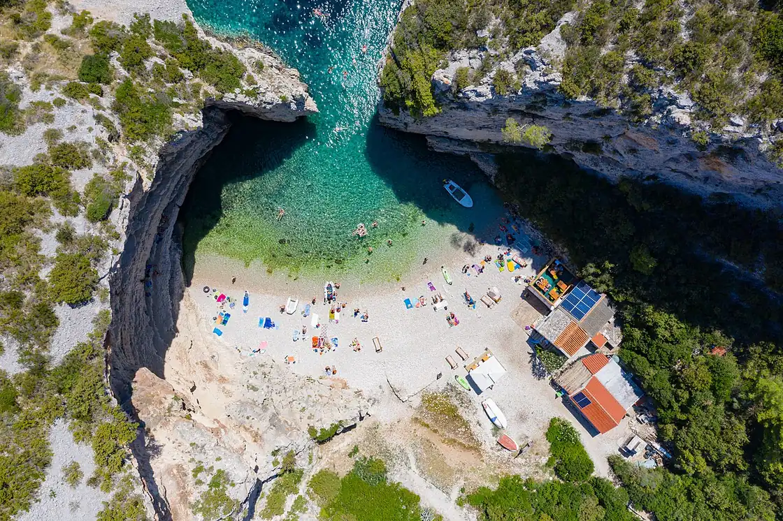 Aerial view of Stiniva cove on Vis, a near-enclosed pebble beach reached through a narrow gap in the cliffs