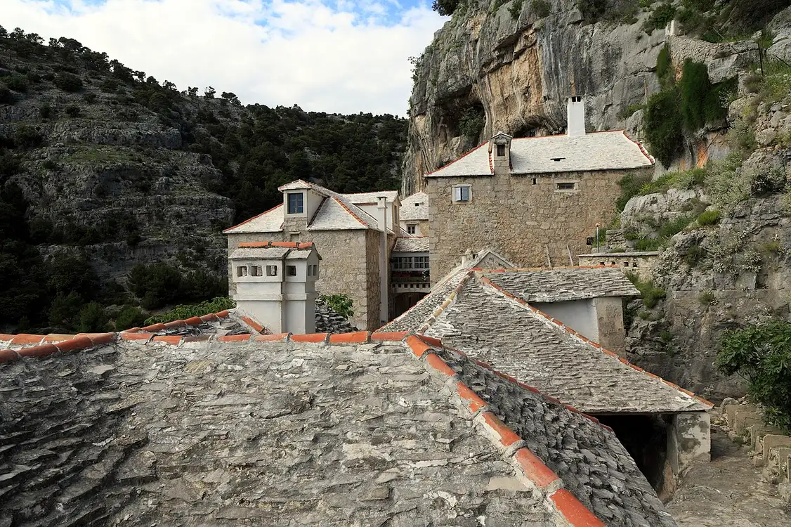 The stone buildings of the Blaca Hermitage tucked under cliffs in a gorge on Brač