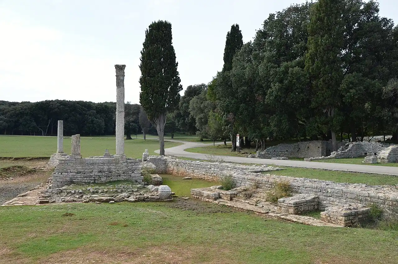 Low stone walls and standing columns of the Roman villa in Verige Bay on Veliki Brijun, framed by cypresses