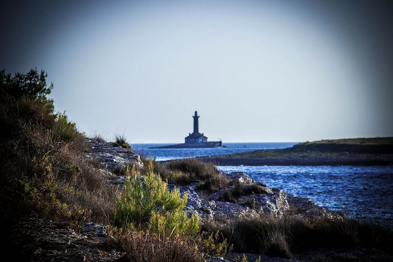 Stone lighthouse and coastal buildings near Premantura at the approach to Cape Kamenjak