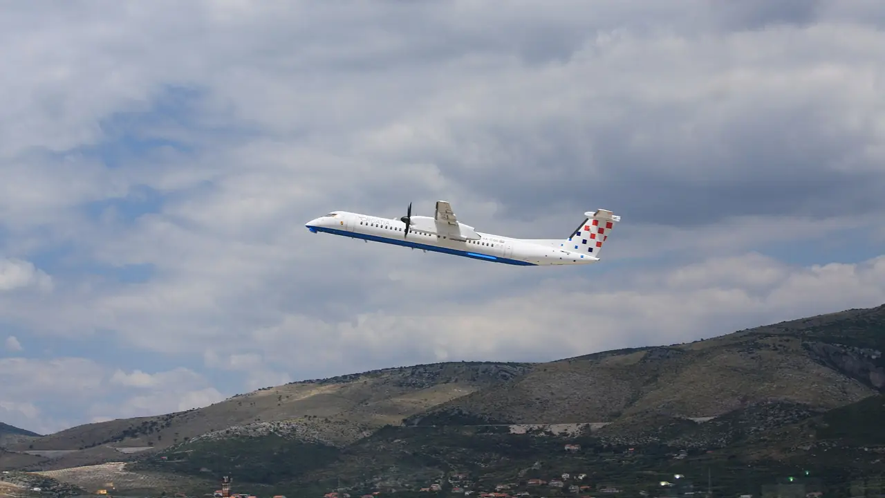 The white tensile canopies over the forecourt of Split Airport, with a taxi and cars at the terminal entrance