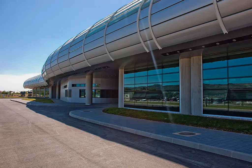 The curved glass frontage of Split Airport's new terminal, with the car park reflected in the windows