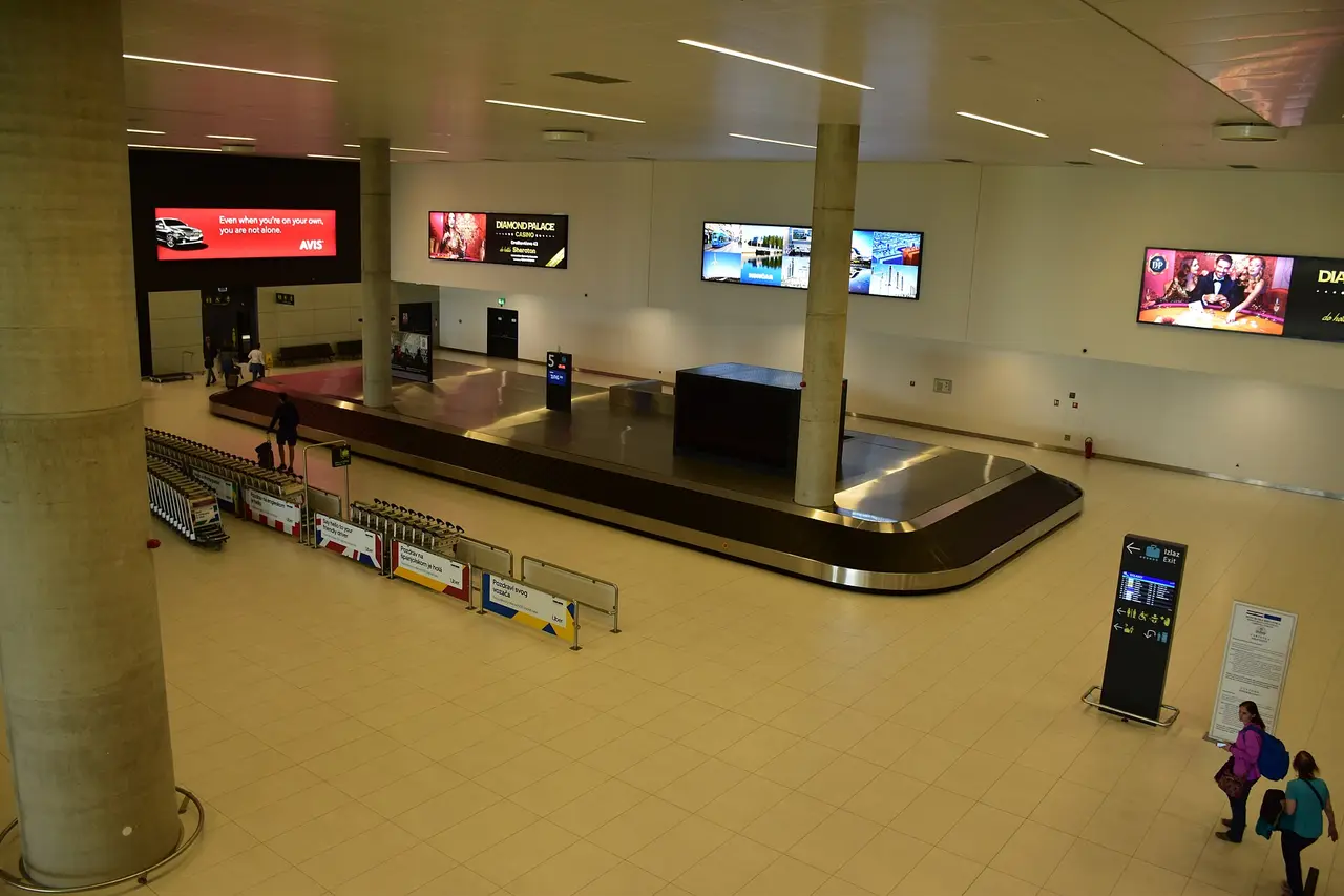 Baggage-claim carousels inside Zagreb Airport arrivals with travellers collecting luggage