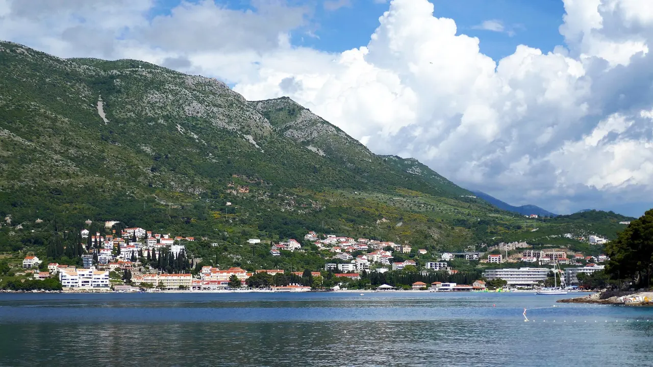 Cavtat spread along its bay beneath a green hillside, seen across the water