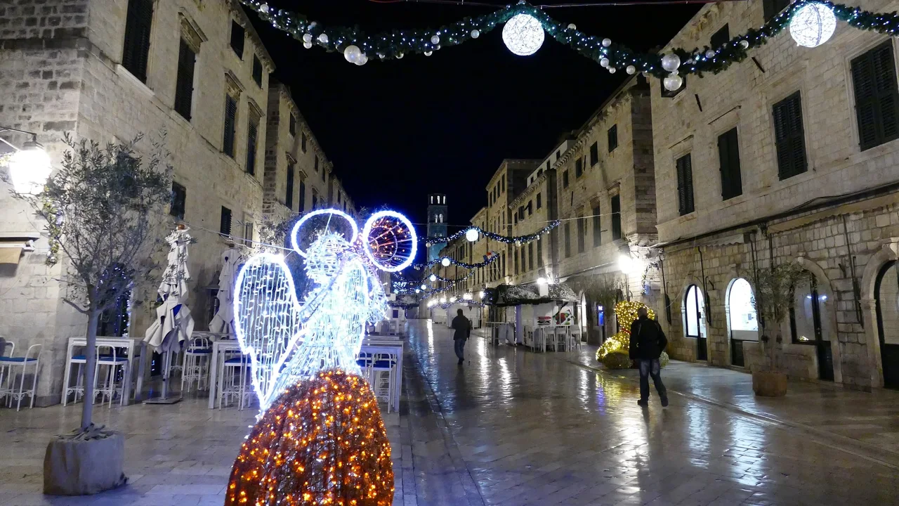 A lit angel figure and garlands strung across Stradun in Dubrovnik's Old Town at night