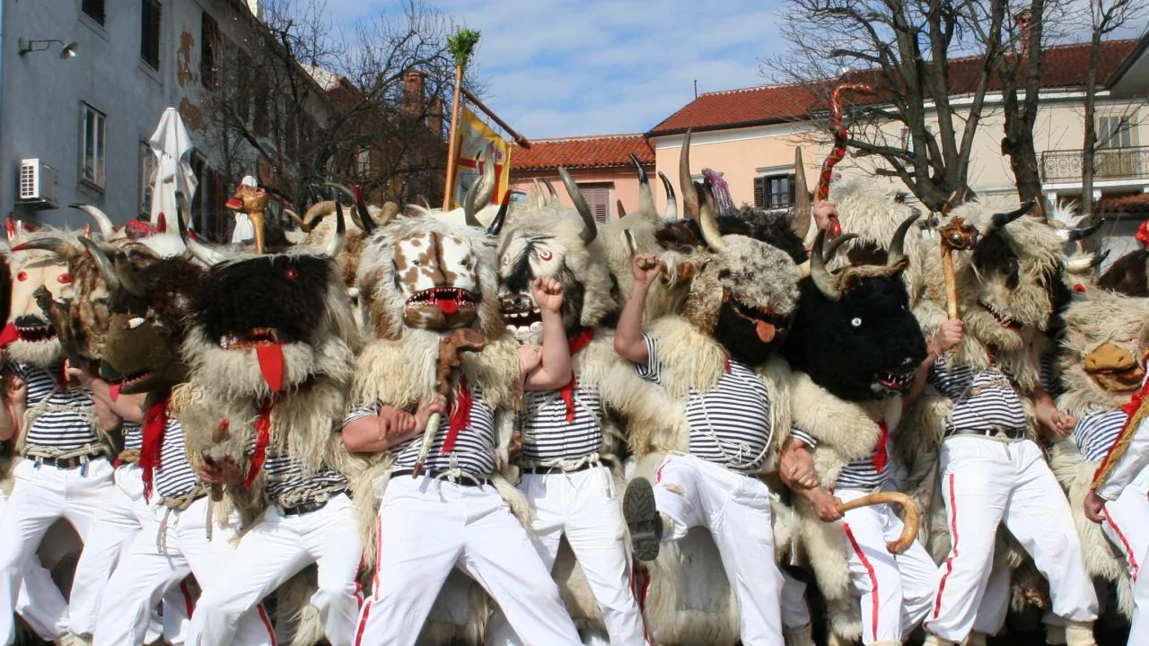 Halubje bell ringers in horned animal masks and sheepskins filling a street during the Kvarner carnival