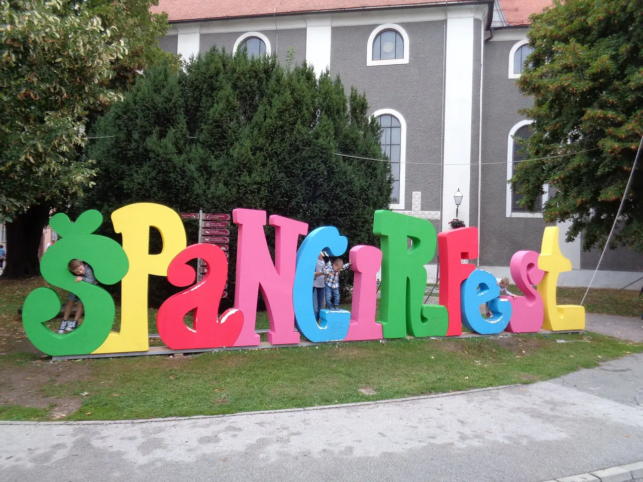 Giant colourful letters spelling Spancirfest on a lawn in Varazdin with children climbing on them