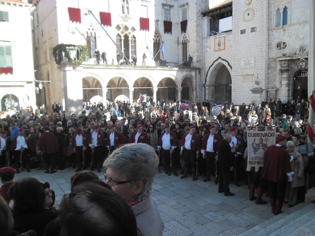 Crowd and men in red cloaks of the Dubrovnik trombunjeri during the Feast of St Blaise in front of Sponza Palace