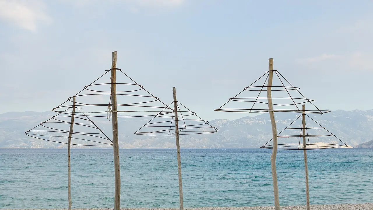 A pebble beach lined with rows of rented sunshades on the Croatian coast at Baška