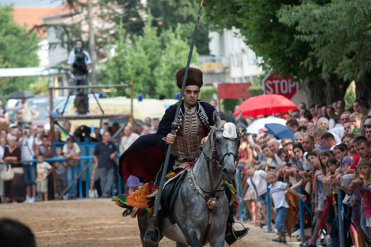 A mounted alkar in eighteenth-century dress uniform galloping down the track at the Sinjska Alka tournament in Sinj