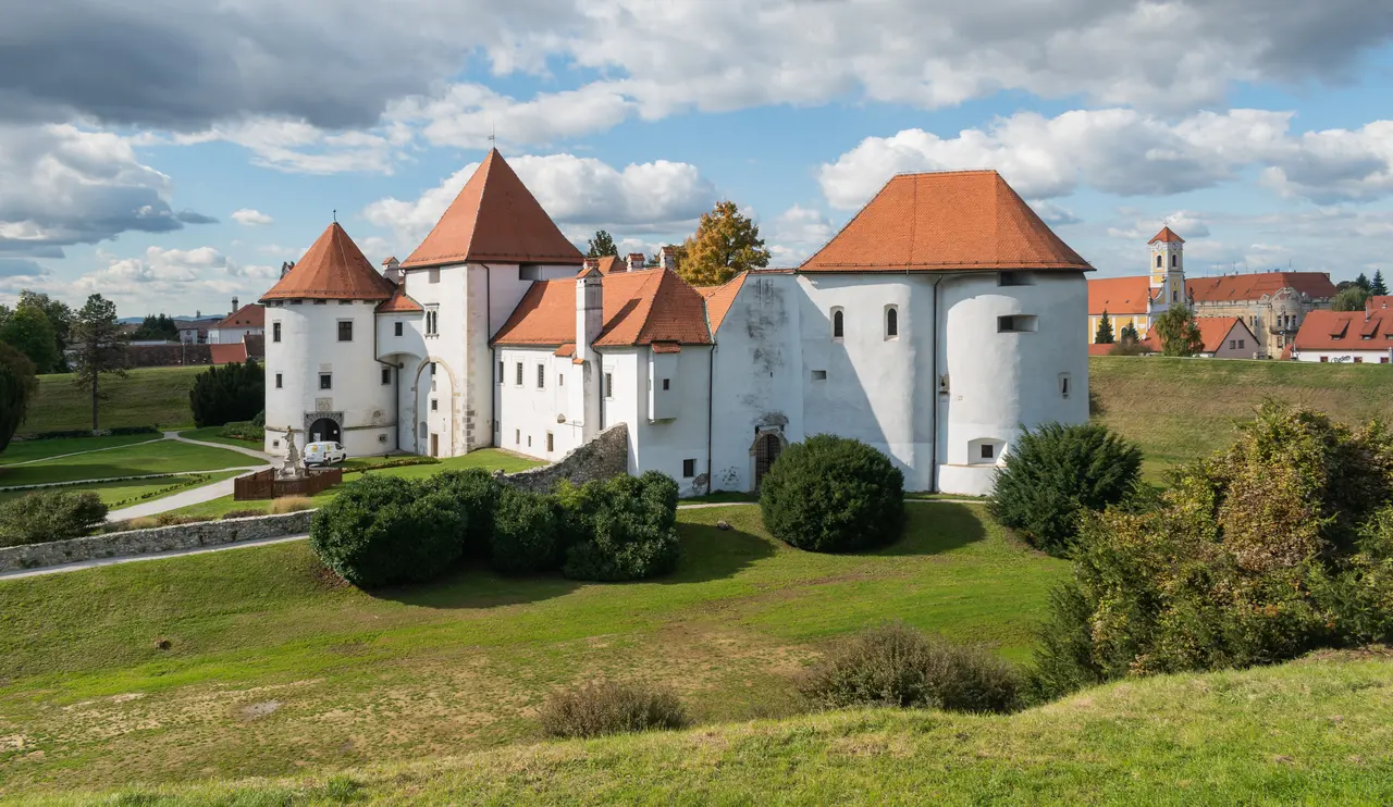The white towers and red roofs of the Old Castle in Varaždin under a partly cloudy autumn sky