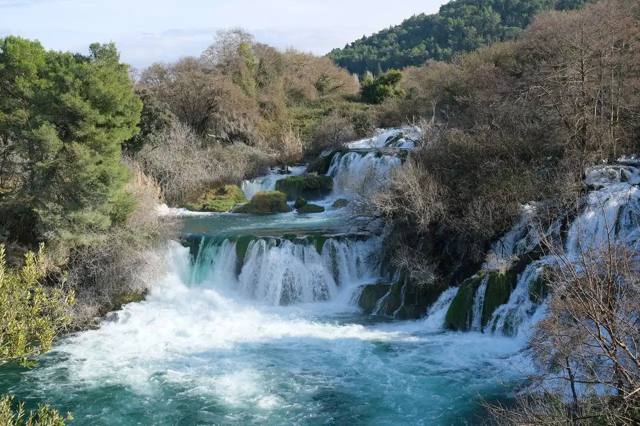 Skradinski Buk cascades with turquoise water and bare winter trees along the banks, with no visitors in sight