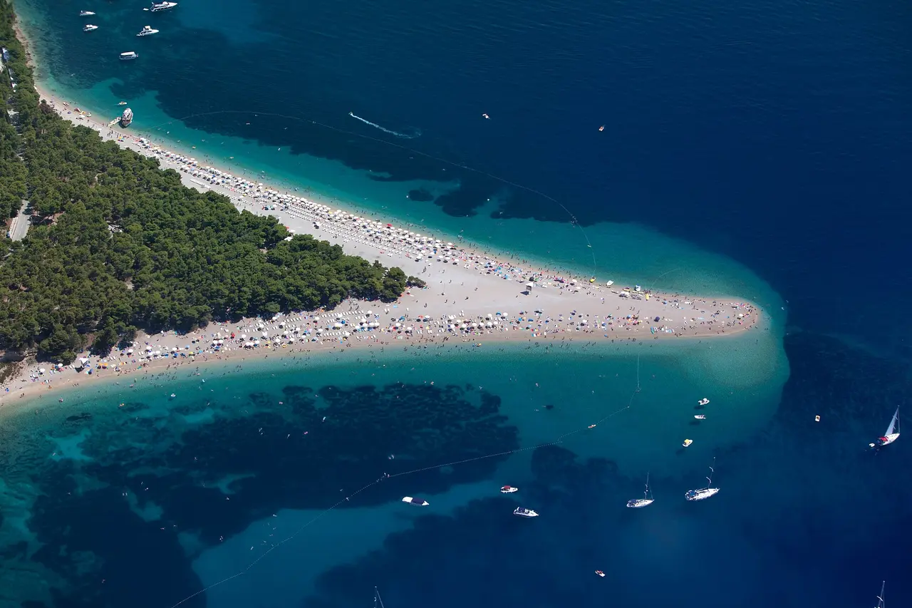 The Zlatni rat pebble beach spit at Bol on Brač, reaching out into clear turquoise sea with pine trees along it