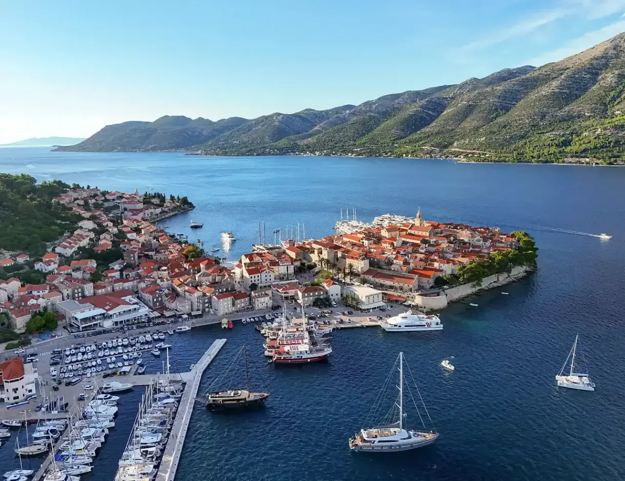Aerial view of the fortified old town of Korčula on its peninsula, the marina and the Pelješac hills behind