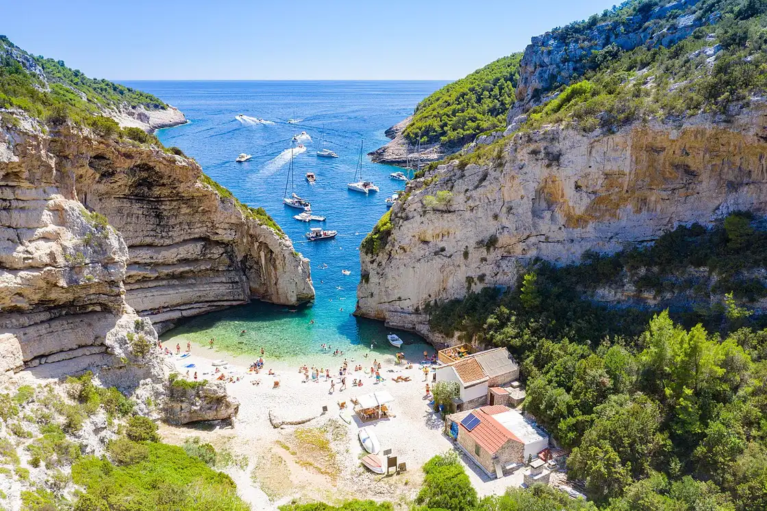 The near-enclosed Stiniva cove on Vis, a pebble beach reached through a narrow gap in tall cliffs