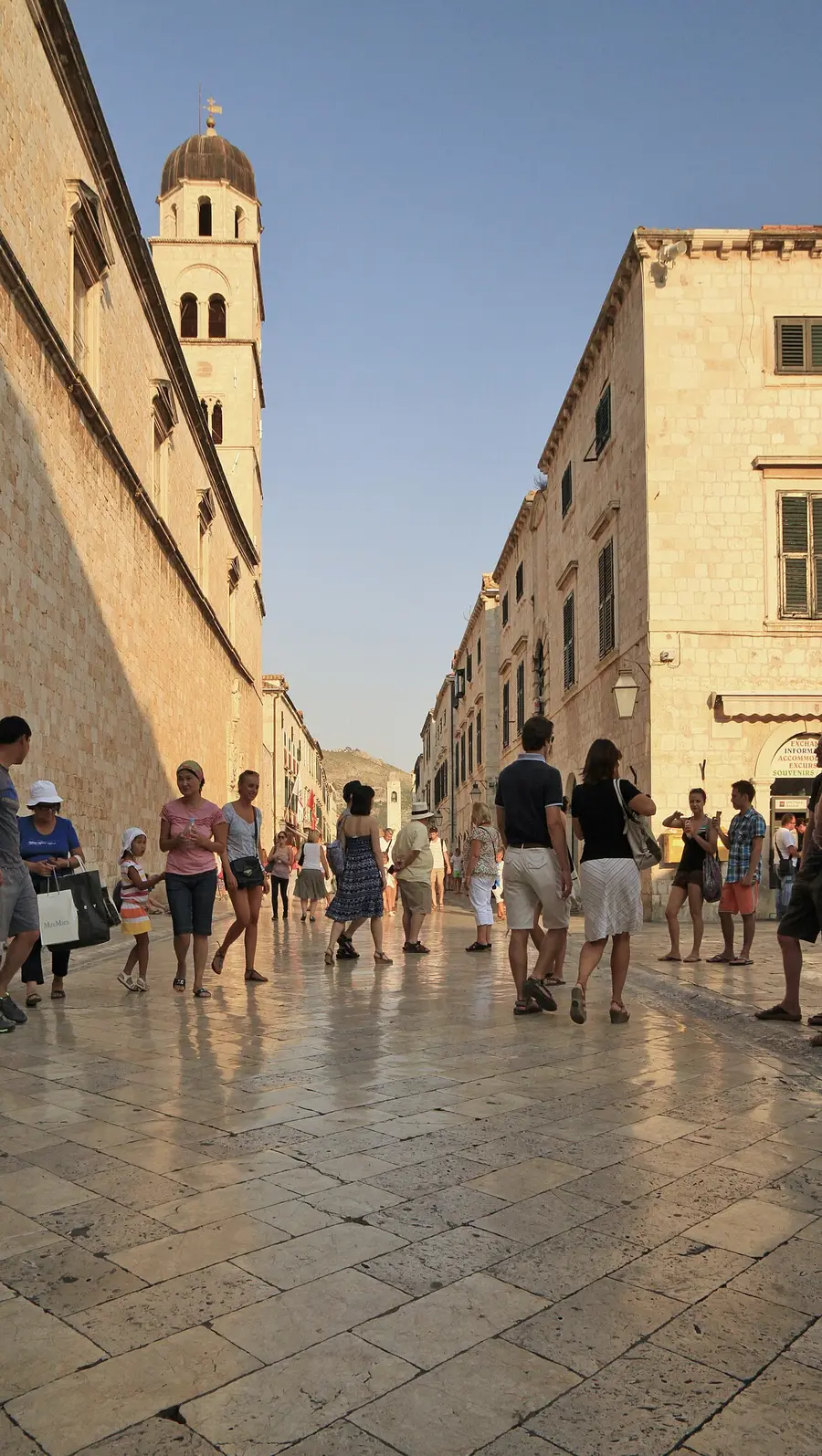 Tourists walking on the polished pale limestone paving of the Stradun in Dubrovnik old town in summer