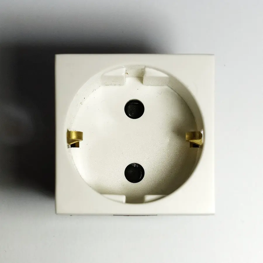 A white European type F Schuko wall socket with two round pin holes and side earthing clips