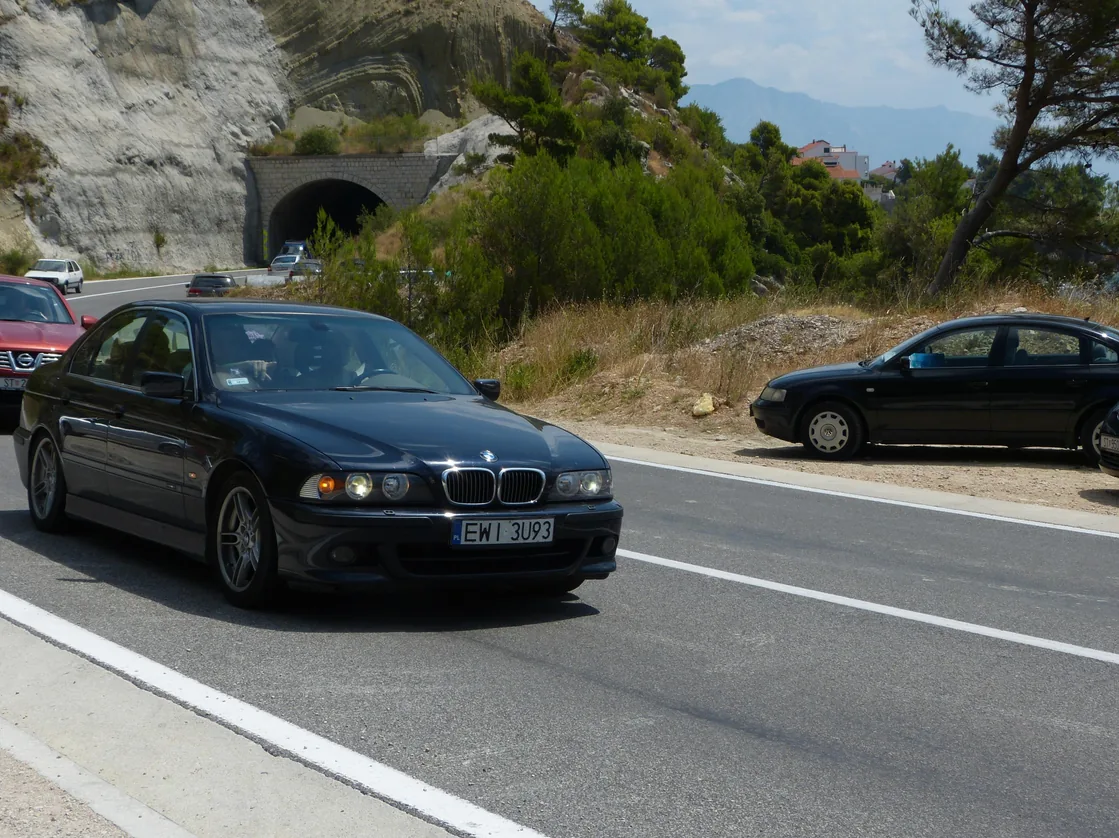 Cars driving the narrow Adriatic coastal highway between rock cuttings in Croatia