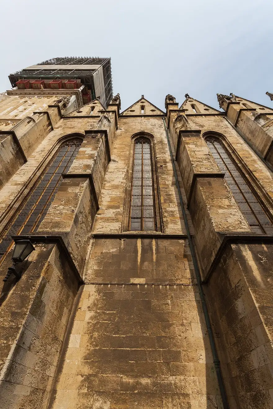 The Gothic twin spires of Zagreb Cathedral seen from below, one spire under restoration scaffolding