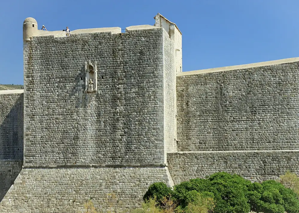 A section of Dubrovnik's medieval stone city walls above the greenery