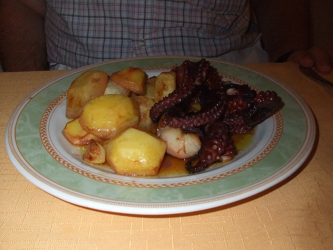 A plate of tender slow-cooked octopus with golden potatoes and olive oil