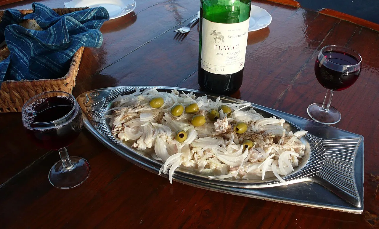 A glass of dark red Plavac Mali wine on a table by the sea
