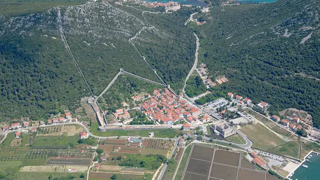 Aerial view of Ston with its long defensive walls climbing the hillside above the salt pans