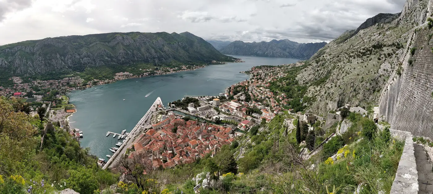 View from the town walls down over the red roofs of Kotor old town and the Bay of Kotor ringed by grey mountains