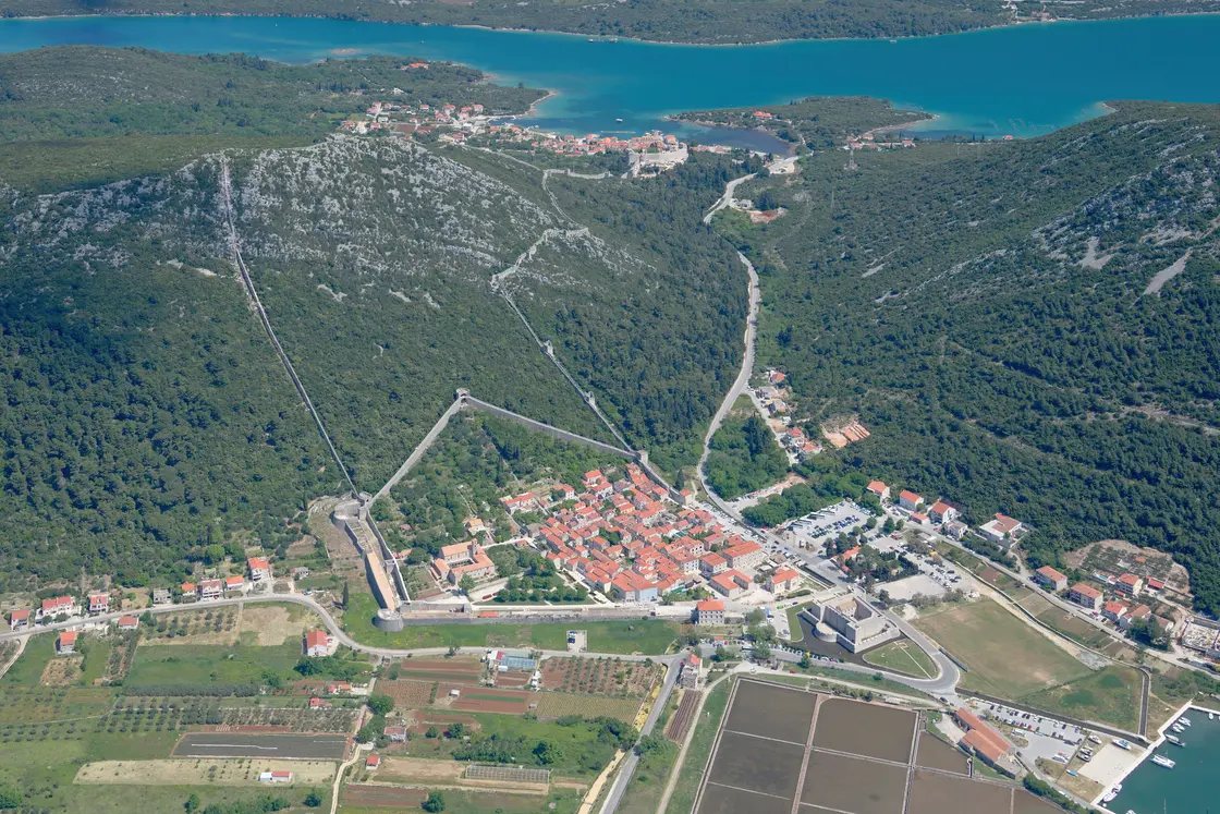 Aerial view of Ston on the Peljesac peninsula, its long stone defensive walls climbing the hills above the town and salt pans