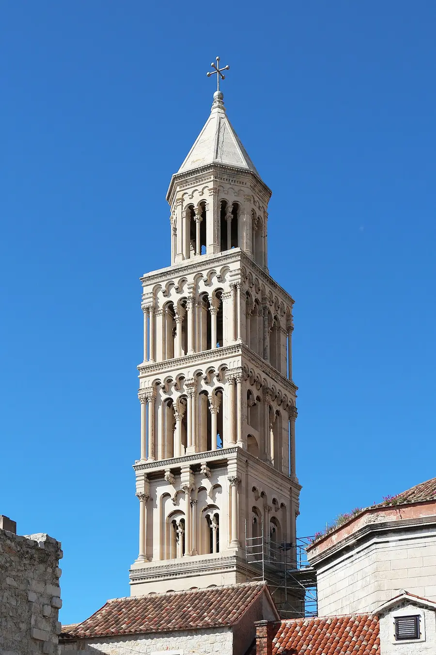The tall Romanesque stone bell tower of the Cathedral of St Domnius rising above the rooftops of Split against a blue sky