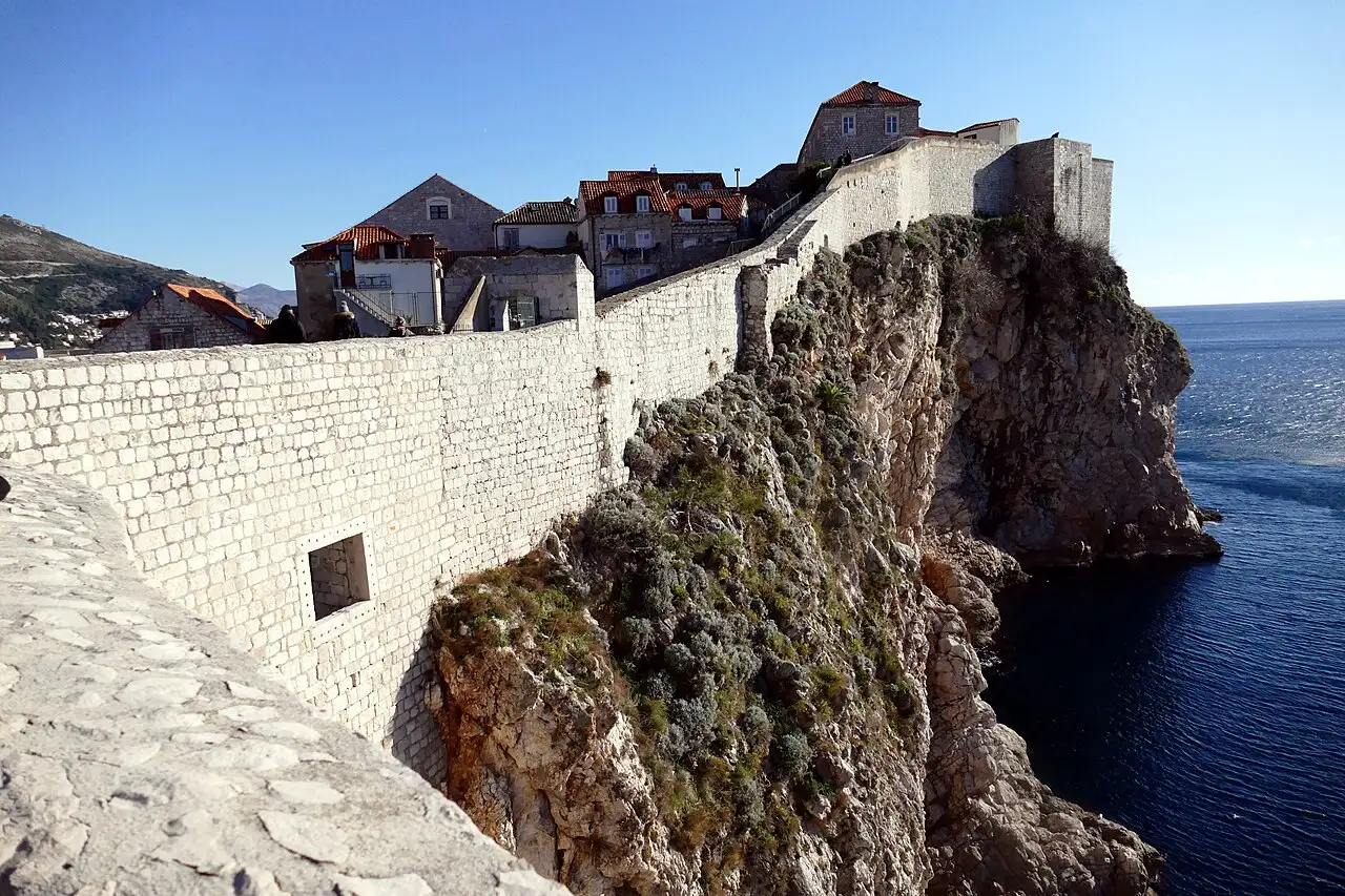 Dubrovnik city walls on the seaward cliff, an old house perched behind the ramparts above the open Adriatic
