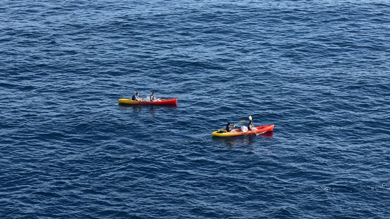 Two double sea kayaks, one yellow and red, on open dark-blue water off Dubrovnik, seen from above