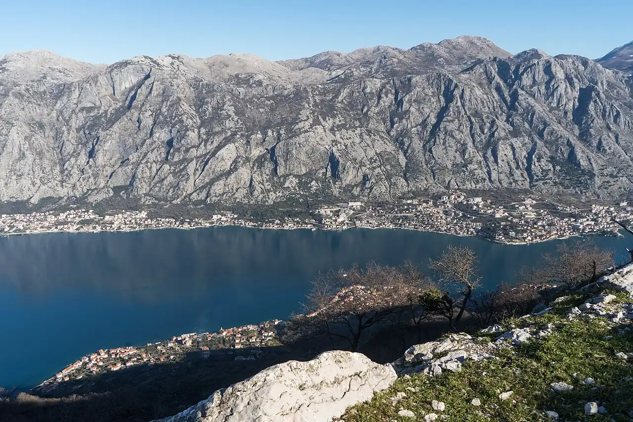 A wide view over the Bay of Kotor from the Vrmac ridge, deep blue water ringed by grey mountains