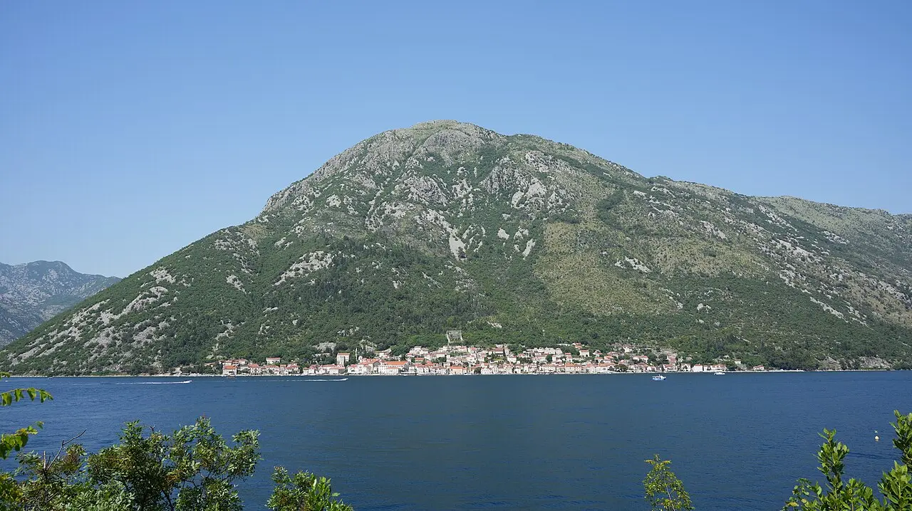 The town of Perast strung along the shore of the Bay of Kotor below a steep green mountain