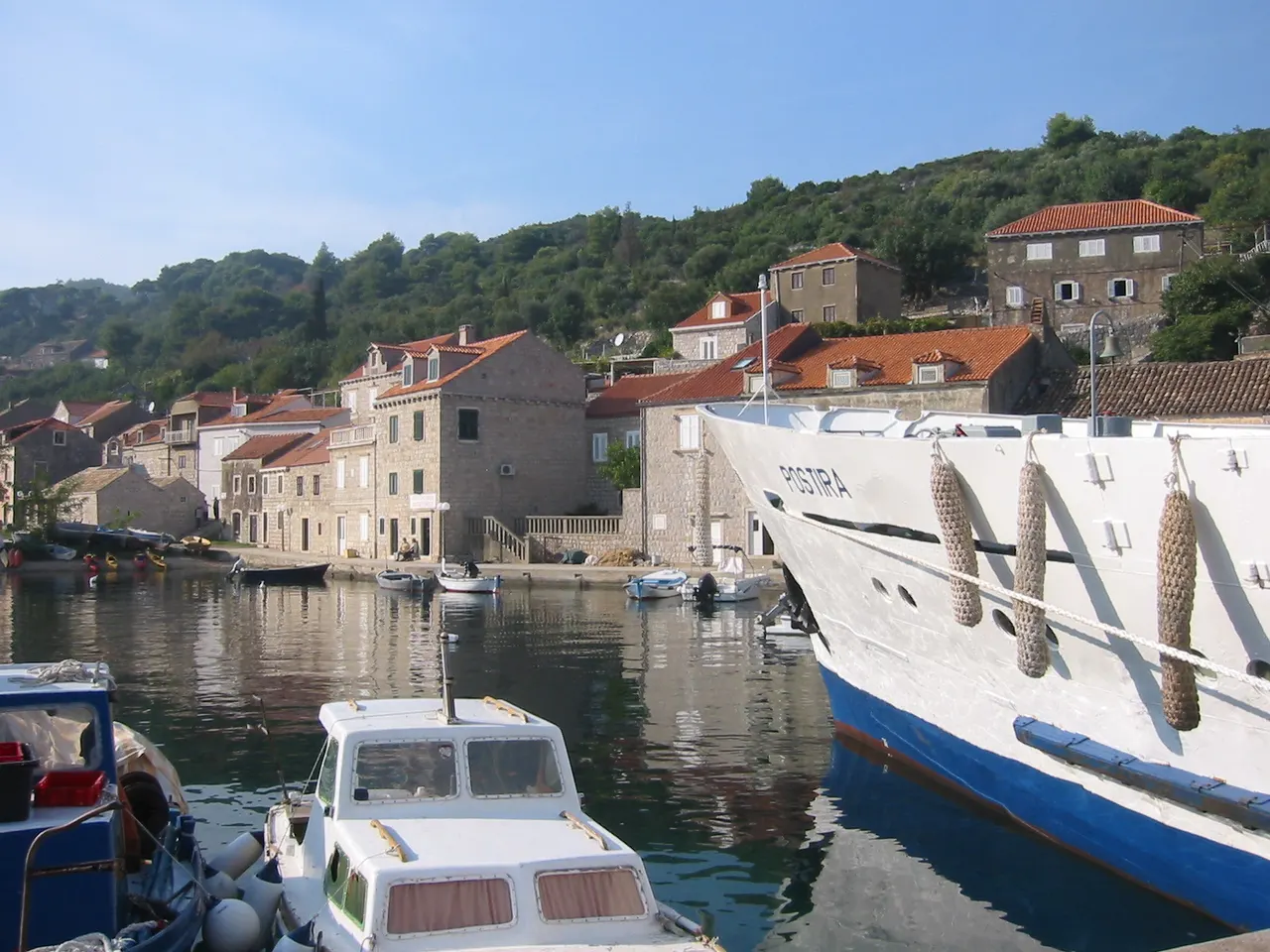 Bow of the Jadrolinija ship Postira alongside stone houses in Suđurađ harbour on Šipan