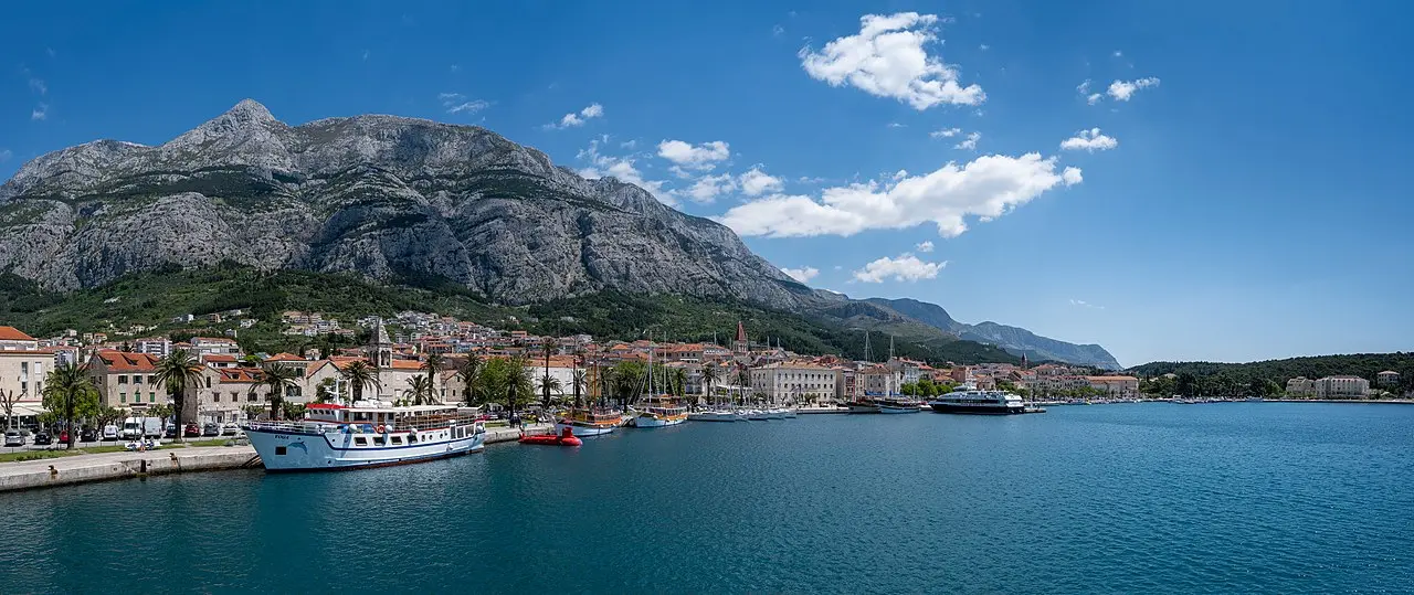 Makarska harbour under the Biokovo mountain, with boats and a ferry along the waterfront