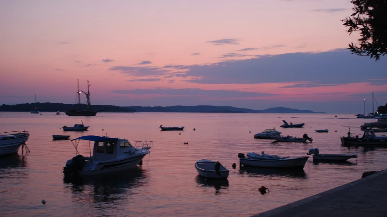Boats on a calm bay at Hvar at dusk under a pink sky