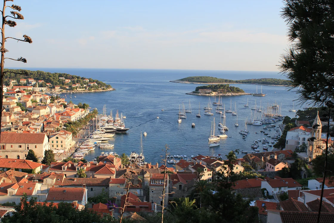 Hvar harbour seen from above with moored boats, the red roofs of the town and the Pakleni Islands in the distance
