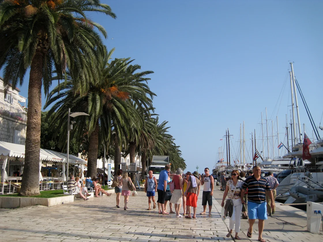 Palm-lined Riva promenade in Hvar Town with yachts moored along it and people strolling