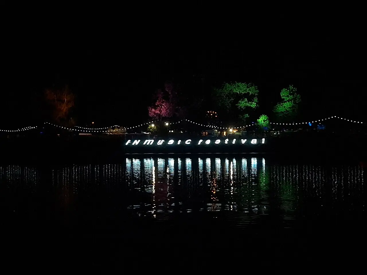 Illuminated INmusic Festival lettering reflected on Lake Jarun at night