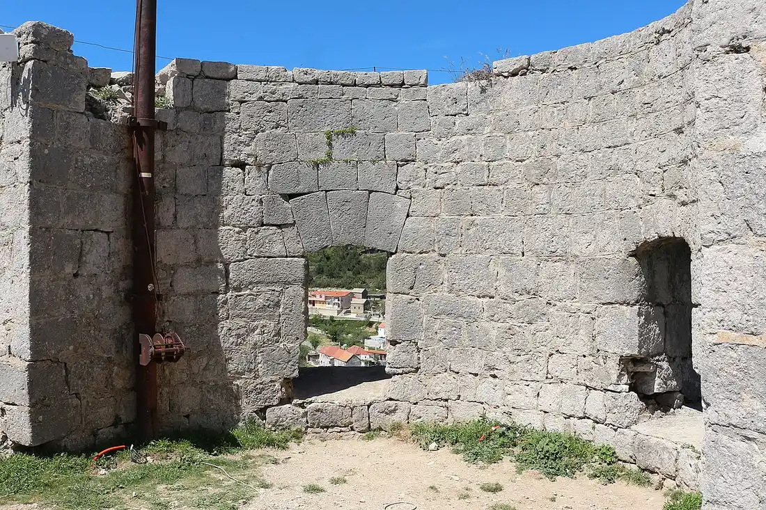 Open stone terrace and battlements of Klis Fortress with hills beyond