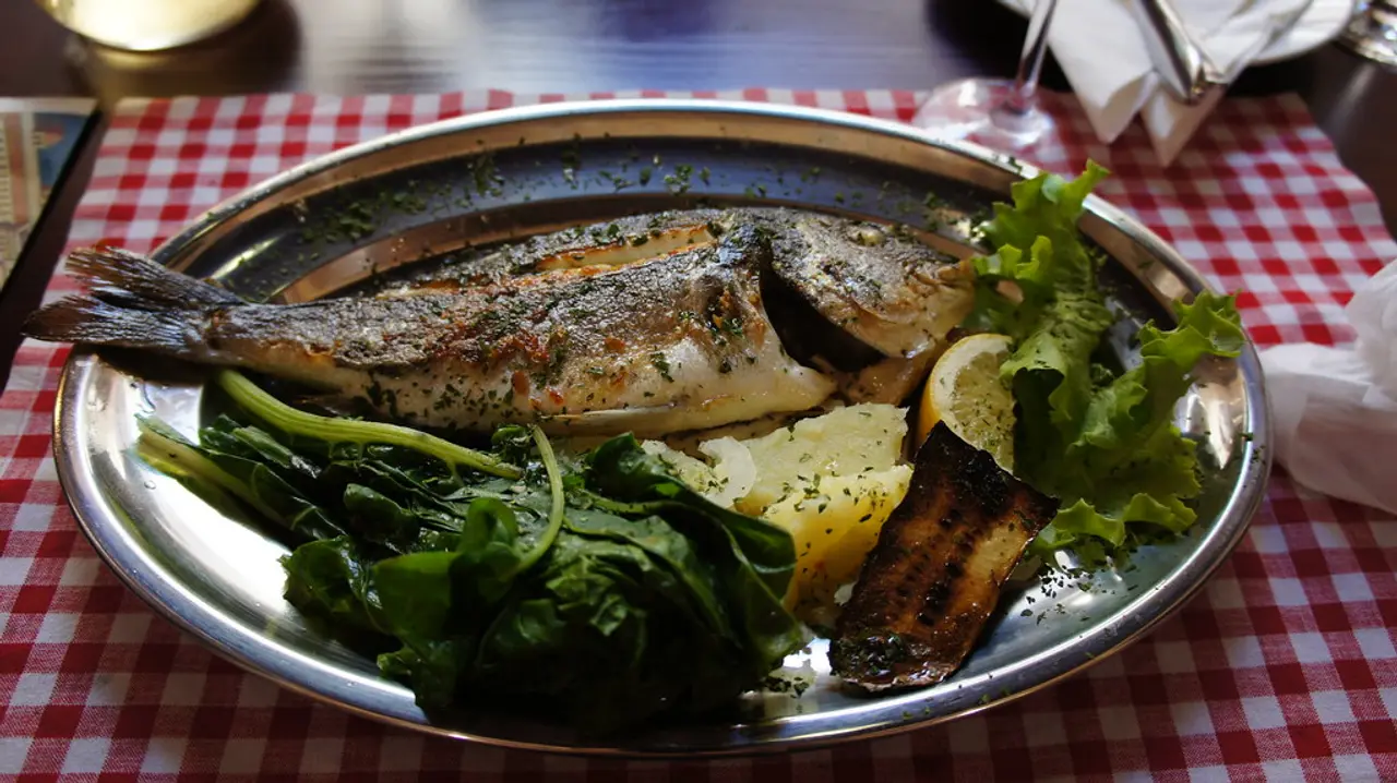 Grilled whole Adriatic fish with chard and potato on a metal platter — a Dalmatian classic